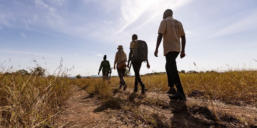 Een groep mensen loopt over de savanne in Tanzania